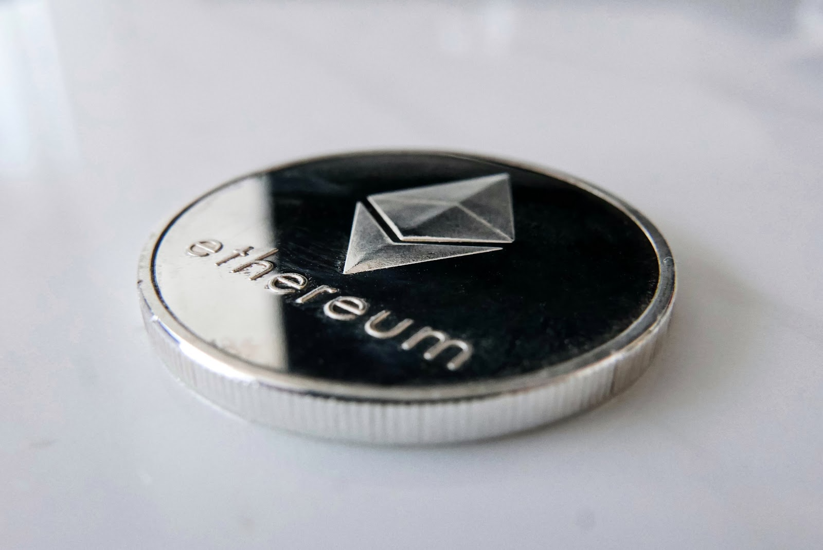 A silver colour Ethereum coin on a white background